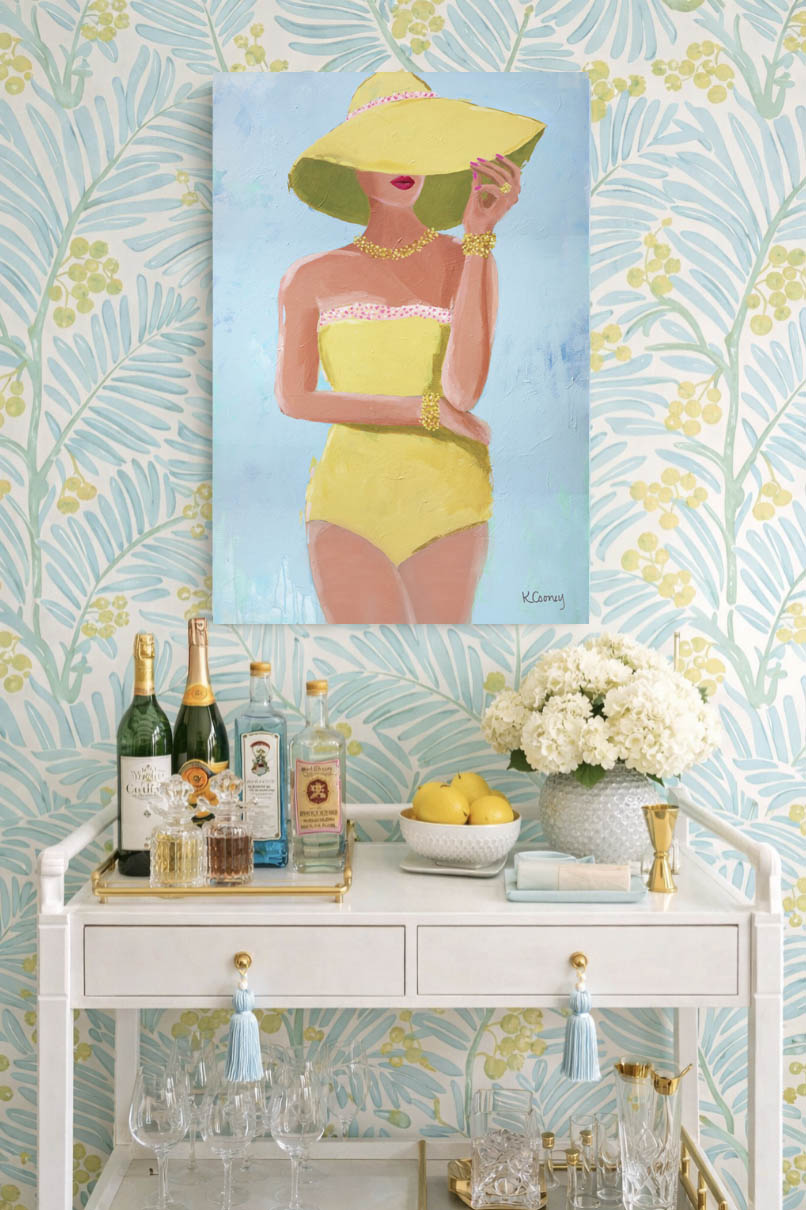 Decorative bar cart in Palm Beach with a painting of a glamorous woman in a yellow swimsuit on a blue background.