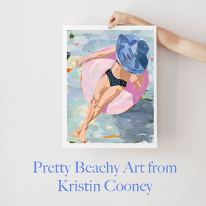 Kristin Cooney's fine art giclee print of a pretty woman in a bikini floating in an innertube in a beautiful water scene, has a feminine palm beach vibe and is the perfect art to add some fun and elegance any home decor, interior design. Printed on Archival Matte Paper Metallic Bamboo frame or natural wood frame.